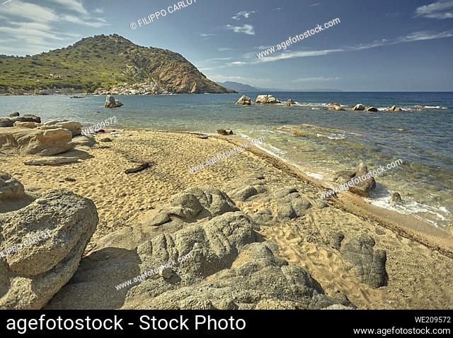 Beautiful seascape of the Cala Sa Figu beach in the south of Sardinia, with the rocks in the foreground, the beach and the curly mountains of vegetation in the...