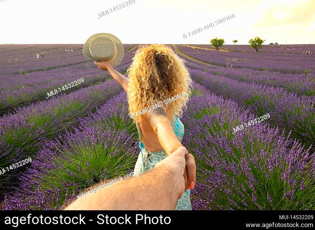 Pov of man holding woman hands with beautiful lavender field in background. Happy couple in travel lifestyle enjoying amazing destination in Europe
