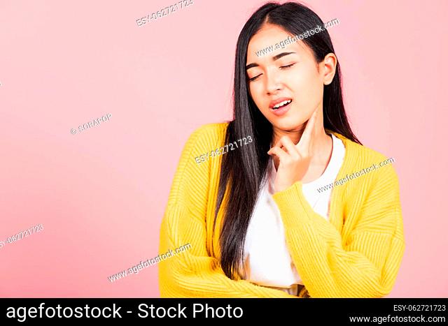Portrait of Asian beautiful young woman has chin pain, female painful use finger touching itching his chin, studio shot isolated on pink background