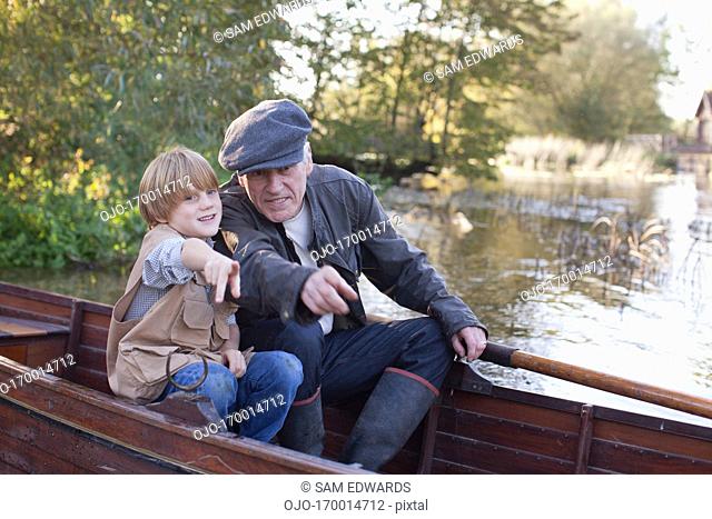 Grandfather and grandson pointing from boat in lake