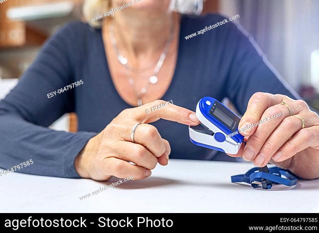 Woman is inserting finger into compact electronic pulse oximeter. Horizontally