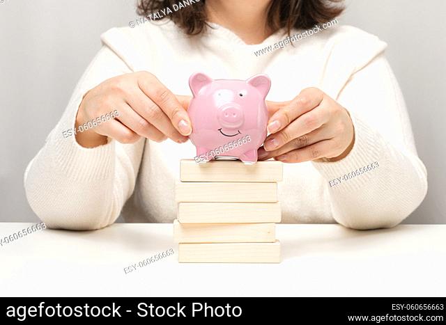 pink ceramic piggy bank and wooden blocks. Concept of increasing interest on a deposit in a bank, high return on investment, large margin on sale