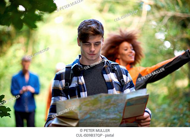 Man hiking with friends in forest looking at map