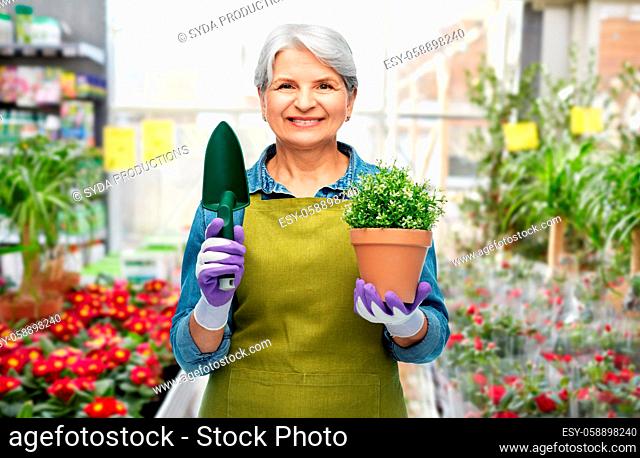 old woman in garden apron with flower and trowel