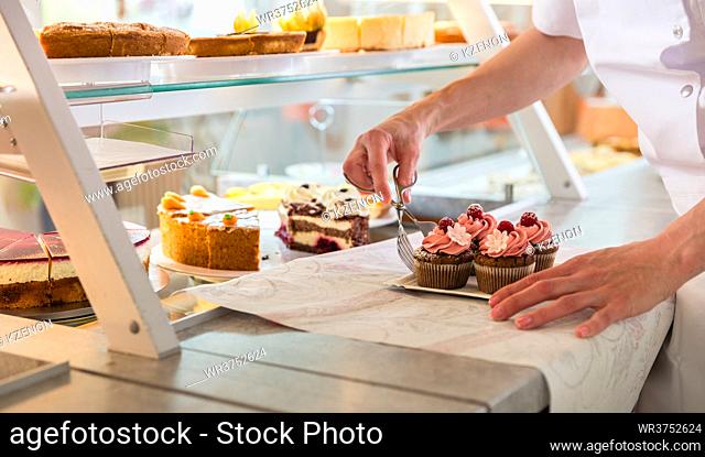 Baker sales woman putting various pies and cakes on display