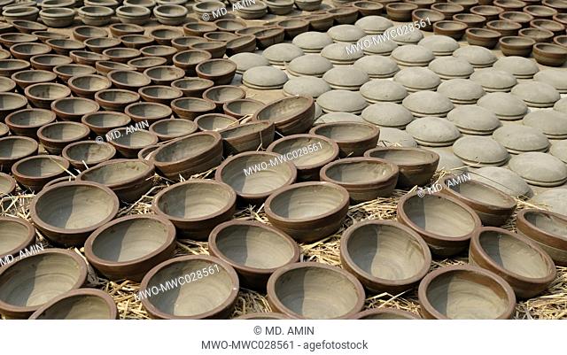 The finished clay pots are left to dry under the sun before they are loaded into kilns for firing. Bangladesh. 2015