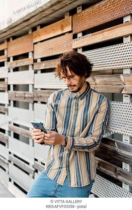 Man wearing striped shirt using smartphone
