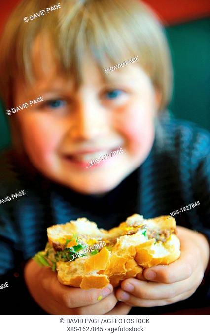 Stock photo of an 11 year old boy eating a burger