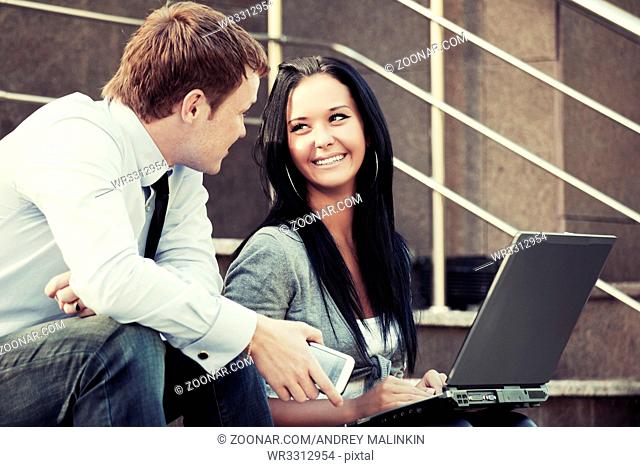 Young business couple using laptop outdoor