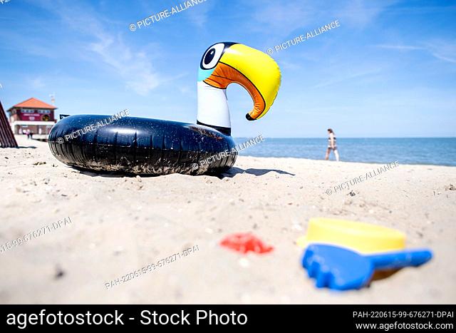 15 June 2022, Lower Saxony, Hooksiel: An inflatable floating animal in the shape of a toucan lies in the sand on the North Sea beach