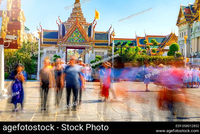 Blurred view of moving tourists visiting Grand Palace in Bangkok, Thailand