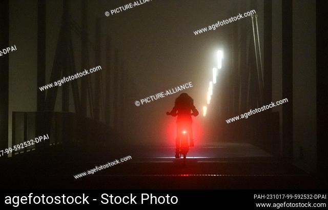 dpatop - 17 October 2023, Lower Saxony, Laatzen: A cyclist rides over a bridge in foggy conditions. Photo: Julian Stratenschulte/dpa