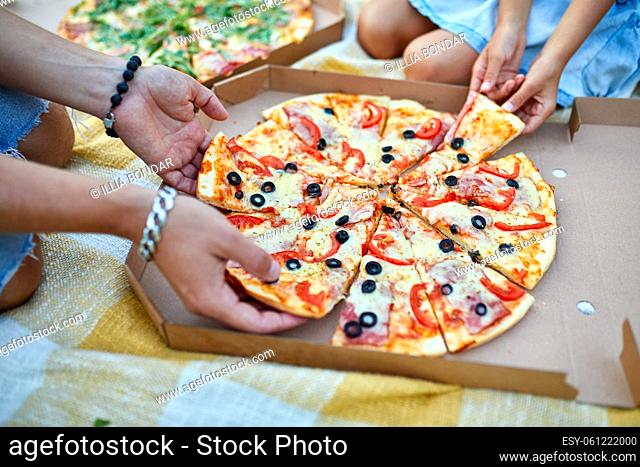 Sharing pizza, hands taking a piece of pizza from a box outdoor, family picnic, eating pizzas for dinner, fast food delivery