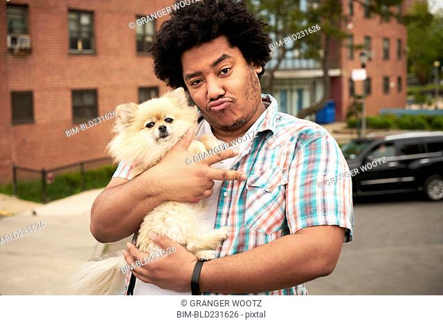 Mixed Race man gesturing peace with dog in city