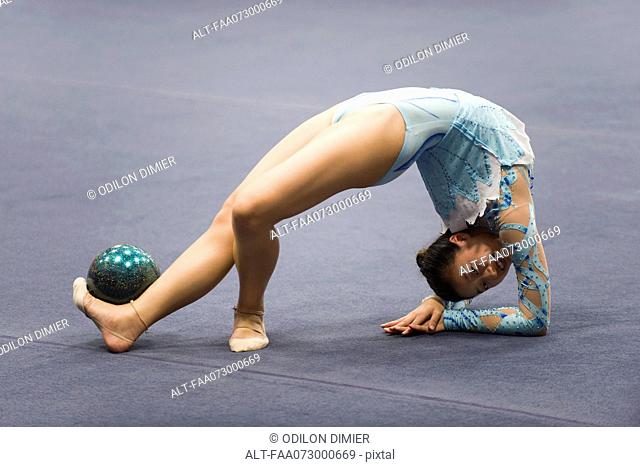 Female gymnast performing floor routine with ball