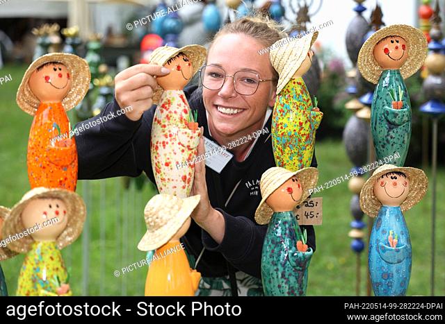 13 May 2022, Saxony-Anhalt, Döbbelin: Exhibitor Janine Bockus from Bamberg , straightens her ceramic gardeners. For the eighth time takes place on 8 hectares...