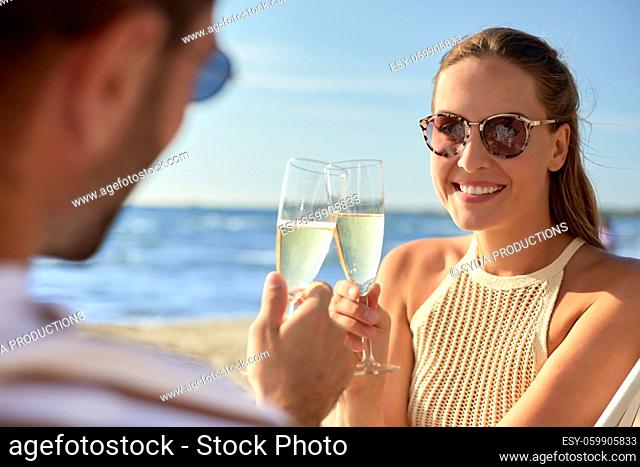 happy couple drinking champagne on summer beach