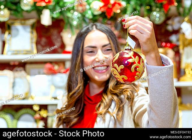 Happy woman holding red bauble in store
