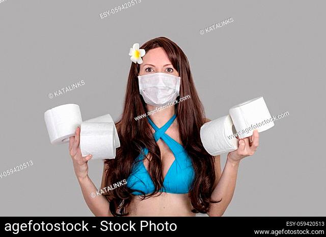 Frightened tourist woman in a medical mask holding toilet paper rolls, the concept cant cross the border back home, flights canceled