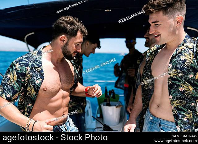 Bearded man dancing with male friends on yacht during vacation