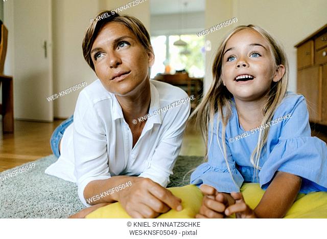 Mother and daughter lying on the floor at home watching something