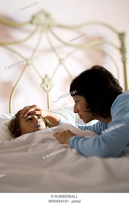 High angle view of a mother checking her daughters temperature