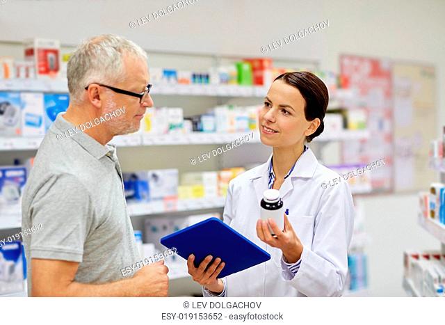 medicine, pharmaceutics, health care and people concept - happy pharmacist with tablet pc computer showing drug to senior man customer at drugstore