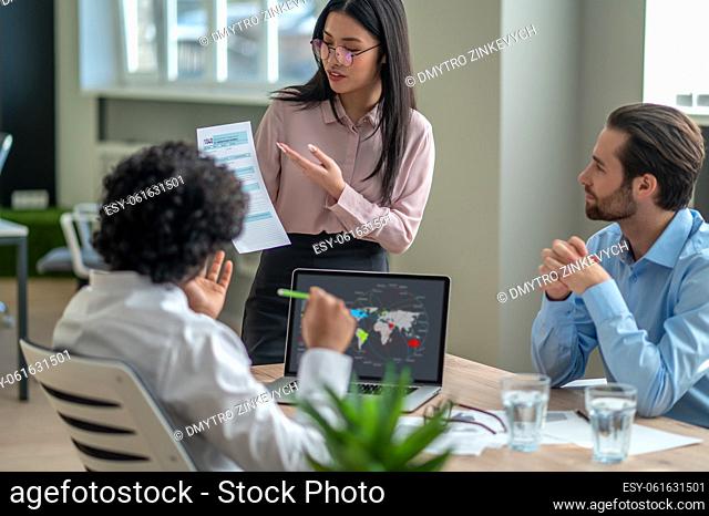 Presentation. Long-haired brunette talking with business partners in the office