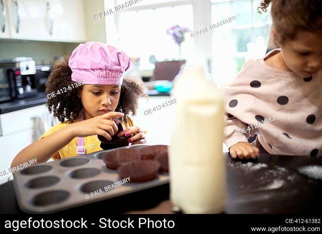 Focused girl baking cupcakes in kitchen