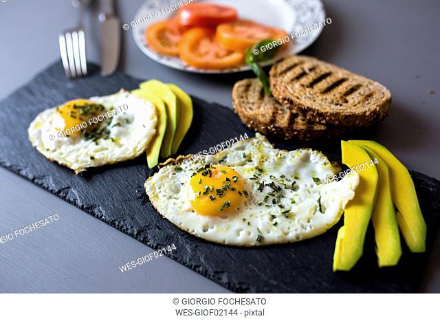 Breakfast with eggs, avovados, tomatoes and toasted bread