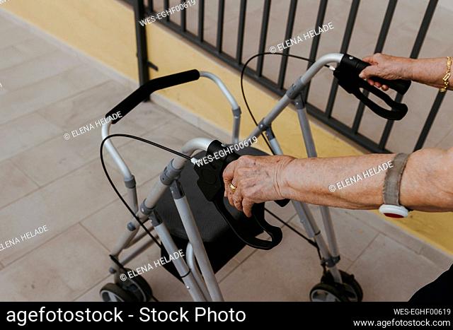Hands of senior woman holding mobility walker on footpath