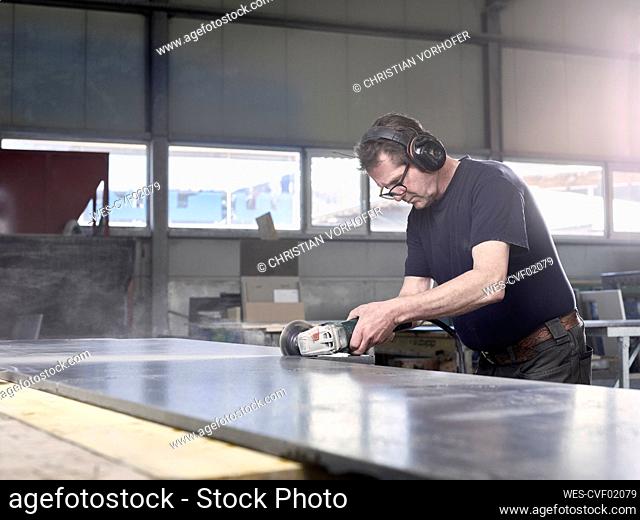 Stonemason cutting marble slab with grinder at workshop