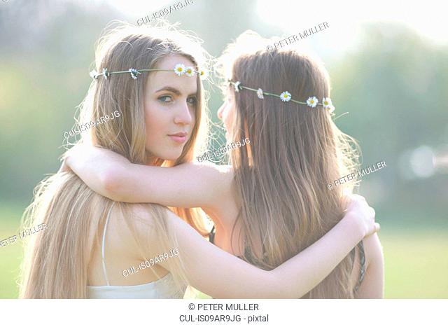 Portrait of two teenage girls wearing daisy chain headdresses in park