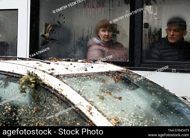 RUSSIA, SOCHI - MARCH 13, 2023: People are seen on a bus driving by the car in Gorkogo Street on which a cypress tree has fallen blocking the traffic in both...