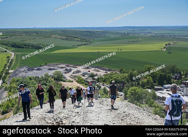 04 June 2023, Saxony-Anhalt, Volkstedt: Visitors climbing to the top of the tailings pile. The tailings pile belongs to the former ""Fortschritt"" copper mining...