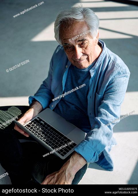 Businessman using laptop while sitting on floor at office