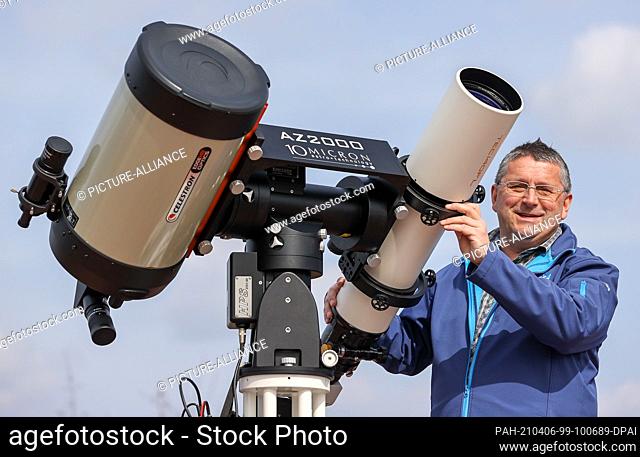 25 March 2021, Saxony, Rodewisch: Olaf Graf, director of the observatory and planetarium, sets up a combination of a new reflecting telescope (l) and a...