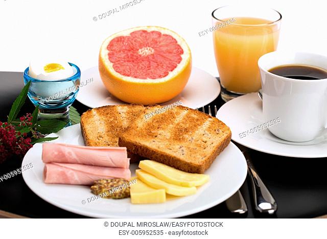 Breakfast with toast, ham, cheese, egg, grapefruit, juice and cup of coffee