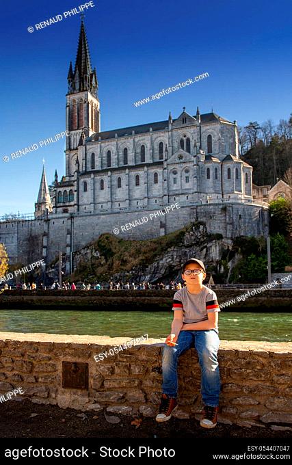 a young boy with the cathedral-sanctuary of Lourdes (France)