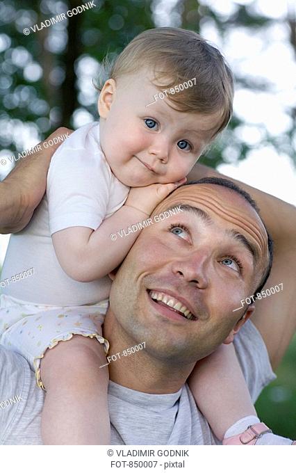 A child sitting on the shoulders of her father
