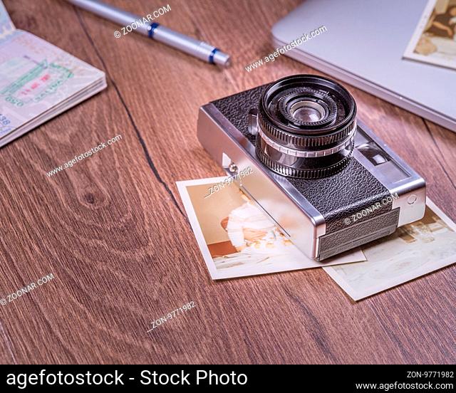 Vintage image with old Camera, old photo, laptop, pen and passport on wood table