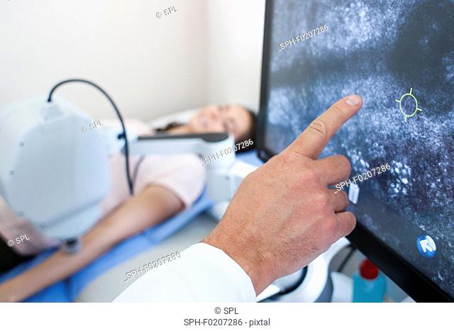 Doctor pointing at computer screen, patient on bed