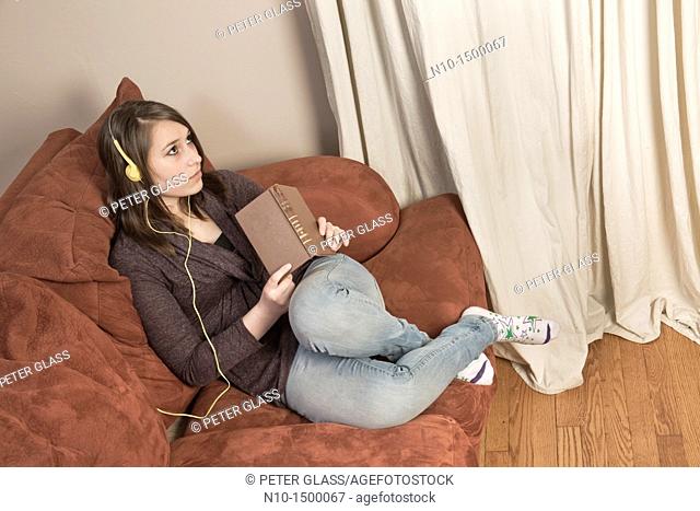 Teen girl, with a book, listening to music on her headset