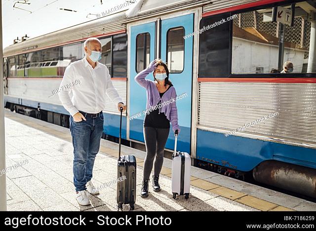 Tourists with suitcases and masks on the platform next to the train, Portugal, Europe