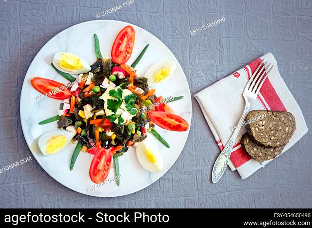 Useful salad of brown seaweed kelp, eggs, carrots, green peas, canned corn, green onions, tomatoes. Healthy diet