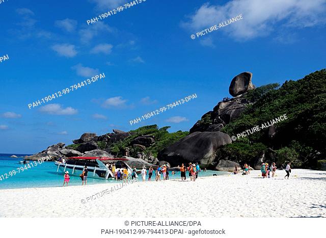 08 March 2019, Thailand, Similan: Tourists walk on the beach of the ""Ao Kuerk"" bay of the island Ko Similan. In the background you can see the rock formation...