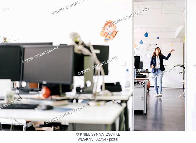 Happy businesswoman juggling balls in office