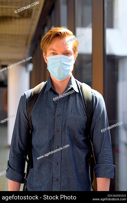 Portrait of young tourist man travelling with mask for protection from corona virus outbreak at the airport