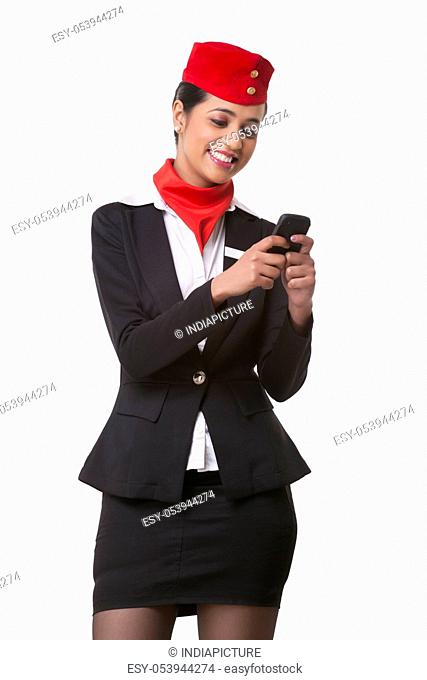 Happy young airhostess messaging on cell phone isolated over white background