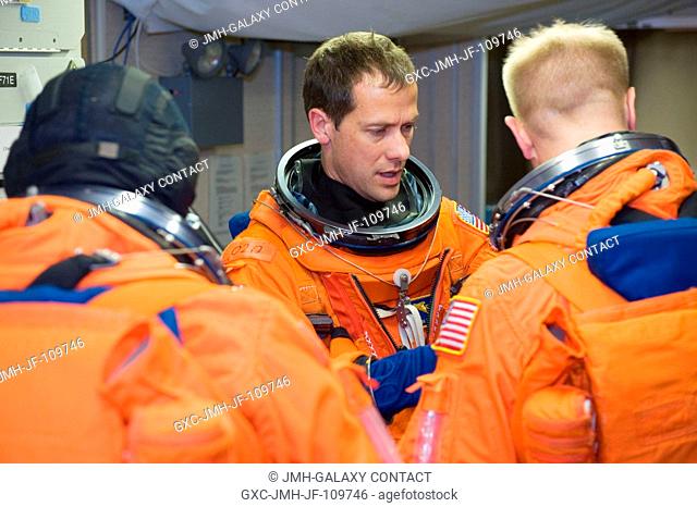 Astronauts Tom Marshburn (center), Tim Kopra, and Dave Wolf (back to camera), all STS-127 mission specialists, attired in training versions of their shuttle...
